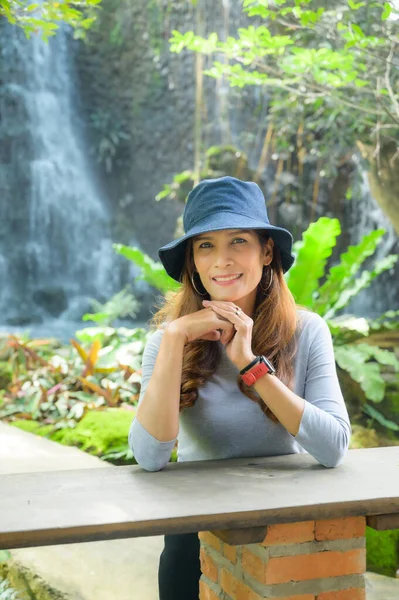 Asian tourist woman with waterfall background in shady garden, Chiang Mai Province.