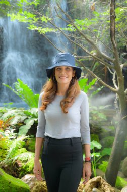 Şelale geçmişi olan Asyalı turist kadın gölgeli bahçede, Chiang Mai Eyaleti.