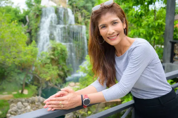 Asian tourist woman with waterfall background in shady garden, Chiang Mai Province.