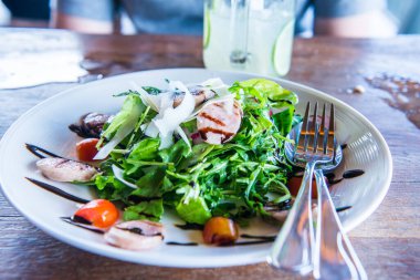 Beyaz tabak üzerinde İtalyan sosisi ve roket salatası, Tayland.