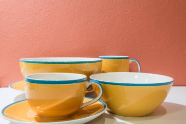 Tabaklar, tabaklar ve bardaklar turuncu duvarlı ve beyaz zemin, Tayland.