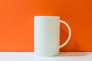 Turuncu duvarlı beyaz seramik bardak ve beyaz zemin, Tayland.