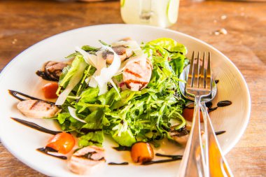 Beyaz tabak üzerinde İtalyan sosisi ve roket salatası, Tayland.