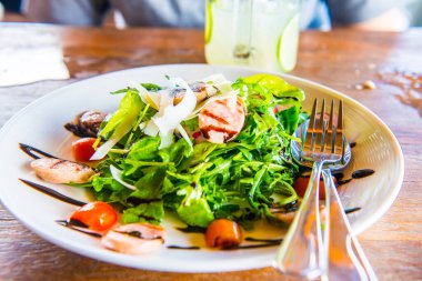 Beyaz tabak üzerinde İtalyan sosisi ve roket salatası, Tayland.