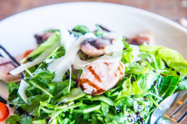 Beyaz tabak üzerinde İtalyan sosisi ve roket salatası, Tayland.