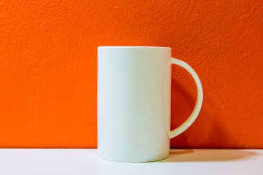 Turuncu duvarlı beyaz seramik bardak ve beyaz zemin, Tayland.