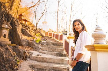 Asian woman with white pagoda background at Tham Phra Sabai temple, Lampang province.