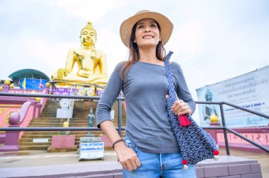 A Woman Traveler with Golden Buddha Background at Golden Triangle, Chiang Rai Province.