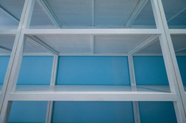 Empty white shelves in blue storage room, Thailand.