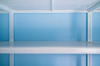 Empty white shelves in blue storage room, Thailand.