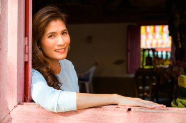 Asian woman in Thai style window frame, Thailand.