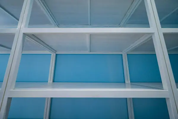 Empty white shelves in blue storage room, Thailand.