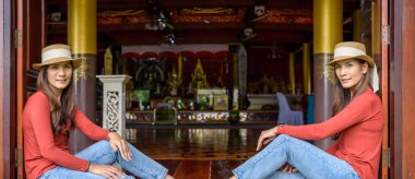 Pamorama of twin Asian women with old building background at Phayao province, Thailand.