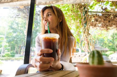 Asian woman in white shirt sitting in a coffee shop at Chiang Mai Province.