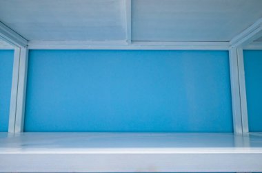 Empty white shelves in blue storage room, Thailand.