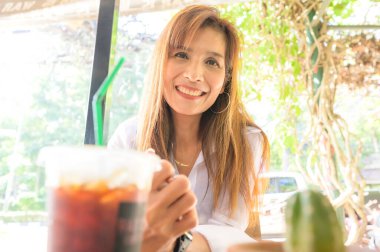 Asian woman in white shirt sitting in a coffee shop at Chiang Mai Province.