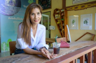 Asian woman in white shirt sitting in a coffee shop at Chiang Mai Province.