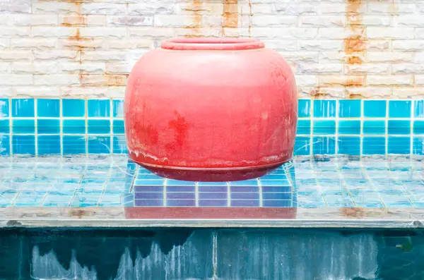 Red water jar in blue pond, Thailand