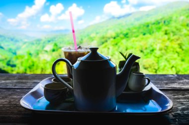 Tahta masada sıcak çay ile seramik çaydanlık yemek için hazır ve Tayland 'ın Chiang Mai eyaletinde dağ manzaralı arka plan.