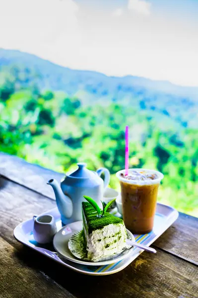 Green tea cake and beverage set with mountain view background at Chiang Mai Province, Thailand.