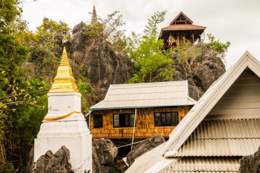 White pagoda and building on mountain at Chaloemphrakiat Prajomklao Rachanusorn temple, Thailand. clipart