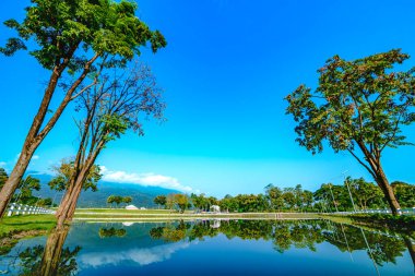 Chiang Mai Serisi: Sakin göl ve dağ manzaralı yeşil ağaçların ortasındaki serin sabah atmosferi. Chiang Mai Eyaleti 'nde egzersiz yapmak için yeşil alanlar. Temiz hava ve güzel manzaralar..