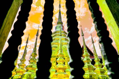 Chiang Mai Serisi: Ahşap pencere parmaklıkları ön planda olan antik bir altın pagoda. Tayland 'ın Chiang Mai eyaletindeki önemli antik siteler. Yaşlı budala ve tahta balyoz önde..