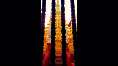Tayland 'daki ahşap pencere parmaklıklarından antik bir altın pagoda görünüyor..