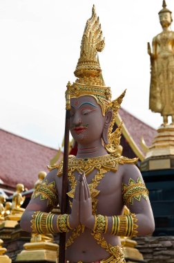 Kahverengi Budist Tayland tapınağında beyaz gökyüzü olan bir heykel dikti..