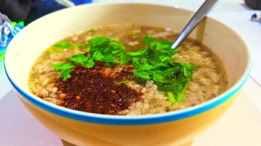 Yemek serisi: yulaf lapası ve sarı kase. Sabahları sıcak yulaf lapası. Biber ve taze sebzeler lapanın üstüne serpilmiş. Domuz kemiği haşlanmış pirinç. Tayland kahvaltısının yemeklerini kapat..