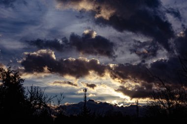 Uzakta saat kulesi olan bulutlu bir gökyüzü.
