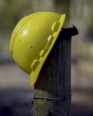 A yellow construction workers helmet on a fence post
