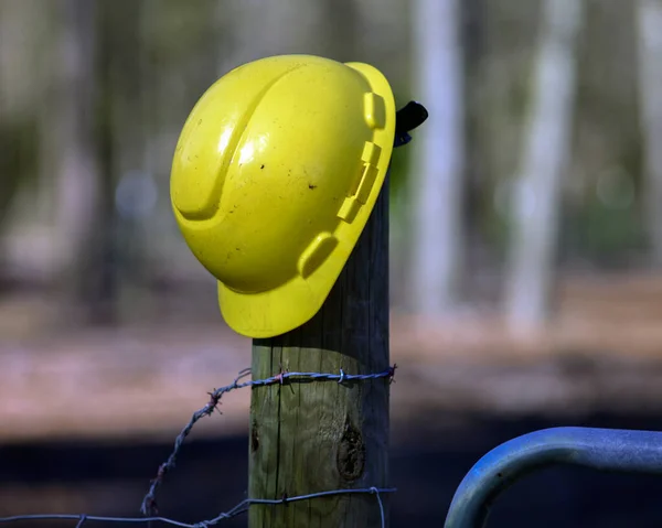 A yellow construction workers helmet on a fence post