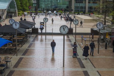 Commuters walking through Reuters Plaza, Canary Wharf, London. Six Public Clocks by Konstantin Grcic.