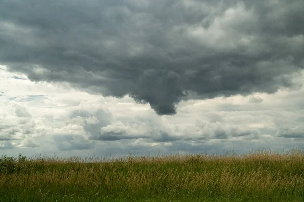 dark storm clouds rolling in across farm field on a late July summer day