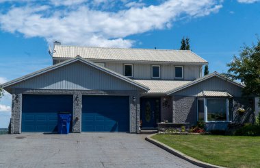 Custom built luxury house with nicely trimmed and landscaped front yard, lawn in a residential neighborhood.- New Liskeard, Ontario - 17 August 2022