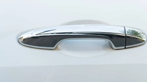 Beautiful chrome car door handle. On the white car floor.