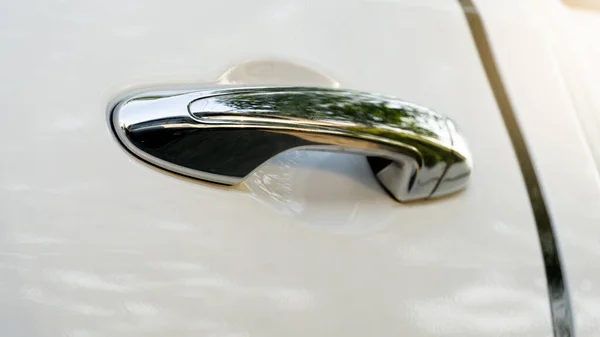 Beautiful chrome car door handle. On the white car floor.