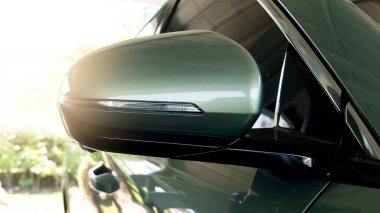 Yumuşak yeşil arabanın ayna kanadının arka tarafında. Kapalı otoparkta dur. Doğanın ve ışığın arka planına sahip.