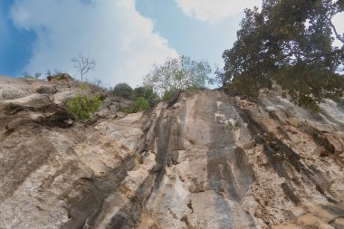 At Wat Tham Khao Bot Tample Wangchan Rayong Tayland ormanında kaya oluşumu. Mavi gökyüzü ve beyaz bulutların altında.