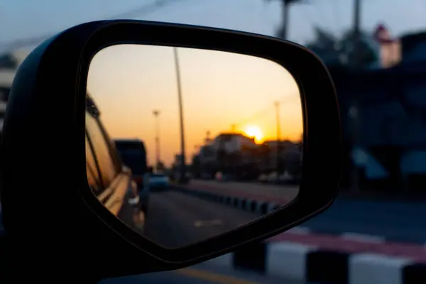 Reflection of the sunset in the car of side mirror view in Thailand. car on the road heading towards the goal of the trip.