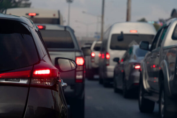 Rear side of dark car with turn on brake light on the road. Traffic jam on the evening. Cars lined up on the road in urgent traffic condition.