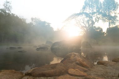 Chaeson Kaplıcaları 'nda suyun yüzeyinden çıkan kayalar. İnce bir buhar tabakasıyla. Sabah sisinin içinden gün ışığı. Chae Son Ulusal Parkı Tayland 'da..