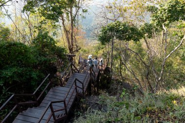 Tanımlanamayan turistler ahşap köprüde seyahat ederler. Ormanlar ve dağlarla çevrili. Wat Chaloem Phra Kiat Phrachomklao Rachanusorn Lampang Tayland 'da.