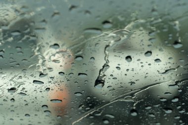 Arabanın camına bir damla yağmur suyu. Diğer arabaların bulanıklığıyla.