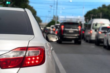 Asfalt yolda beyaz araba durağı lüksü. Aydınlık bir dönemde taşralarda seyahat etmek. Işık frenini aç. Birçok araba uzun bir kuyrukta ileri doğru koştu.