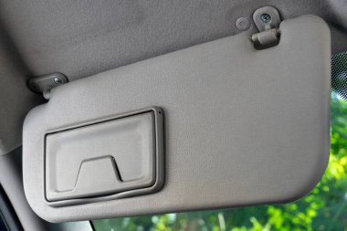 Oğul vizörleri cam paneli kapatır. Arabanın içindeki sürücünün ön görüntüsü. Yeşil ağaç yapraklarının arkaplanı.