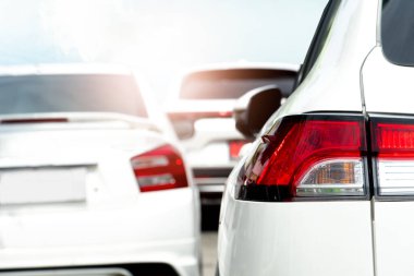 Lüks beyaz arabanın arka lambası. Beyaz arabalar arka arkaya park halinde durur. Parlak gökyüzünün altında.