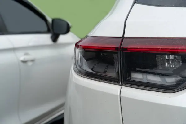 stock image Rear side of white car close on tail light of car. Car parking with other white car. with green background.