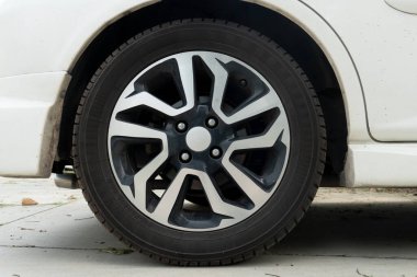 Tekerlek alaşımlı ve alternatif siyah ve gümüş telli çok dilli bir tasarımı var. Lastik siyah ve iyi durumda görünüyor. Arabanın çamurluğu arka planda kısmen görülebilir..